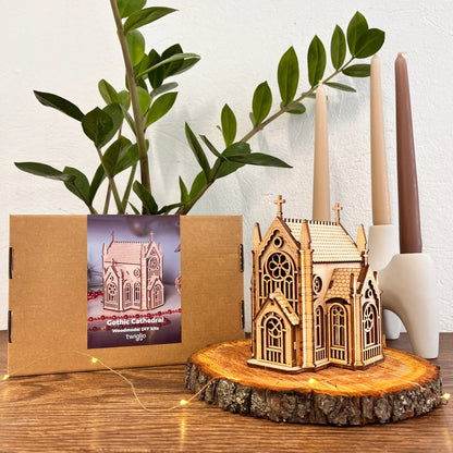 Wooden Gothic cathedral model on a wooden base with packaging and candles in the background