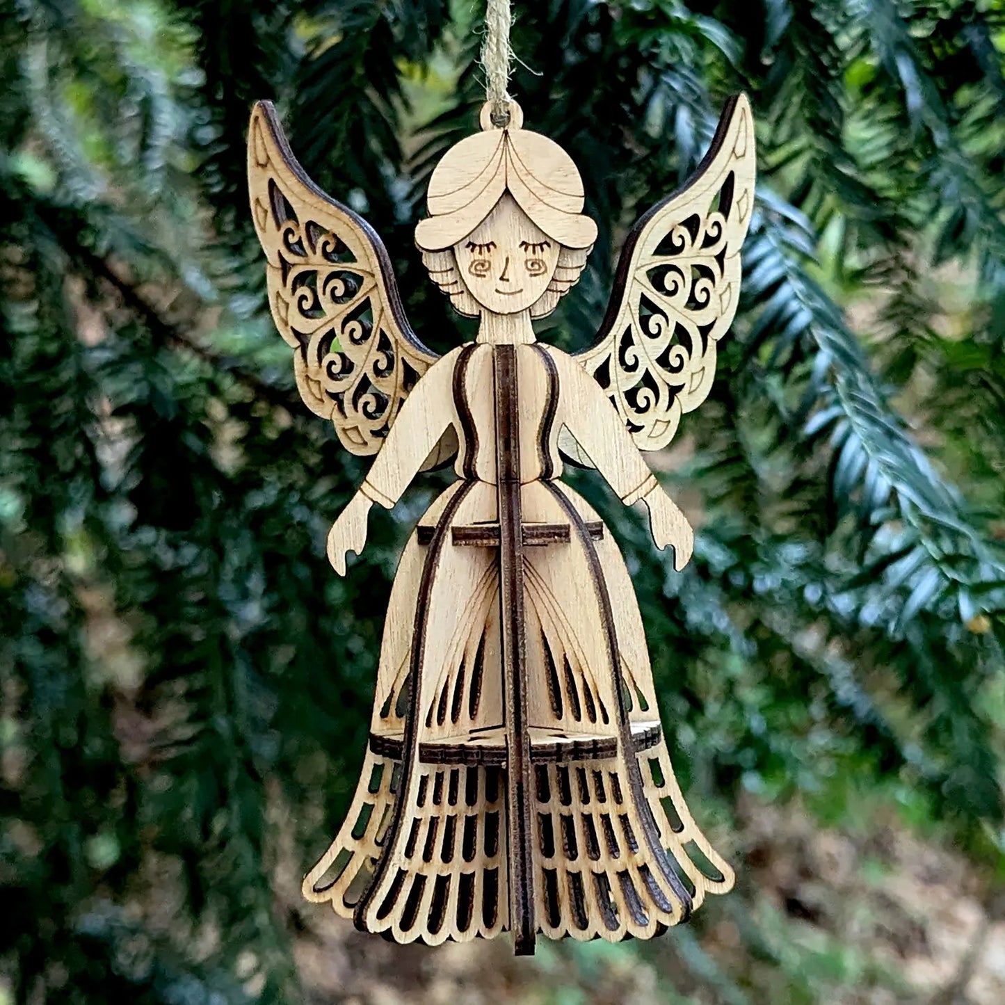 Wooden angel ornament hanging against a green tree background