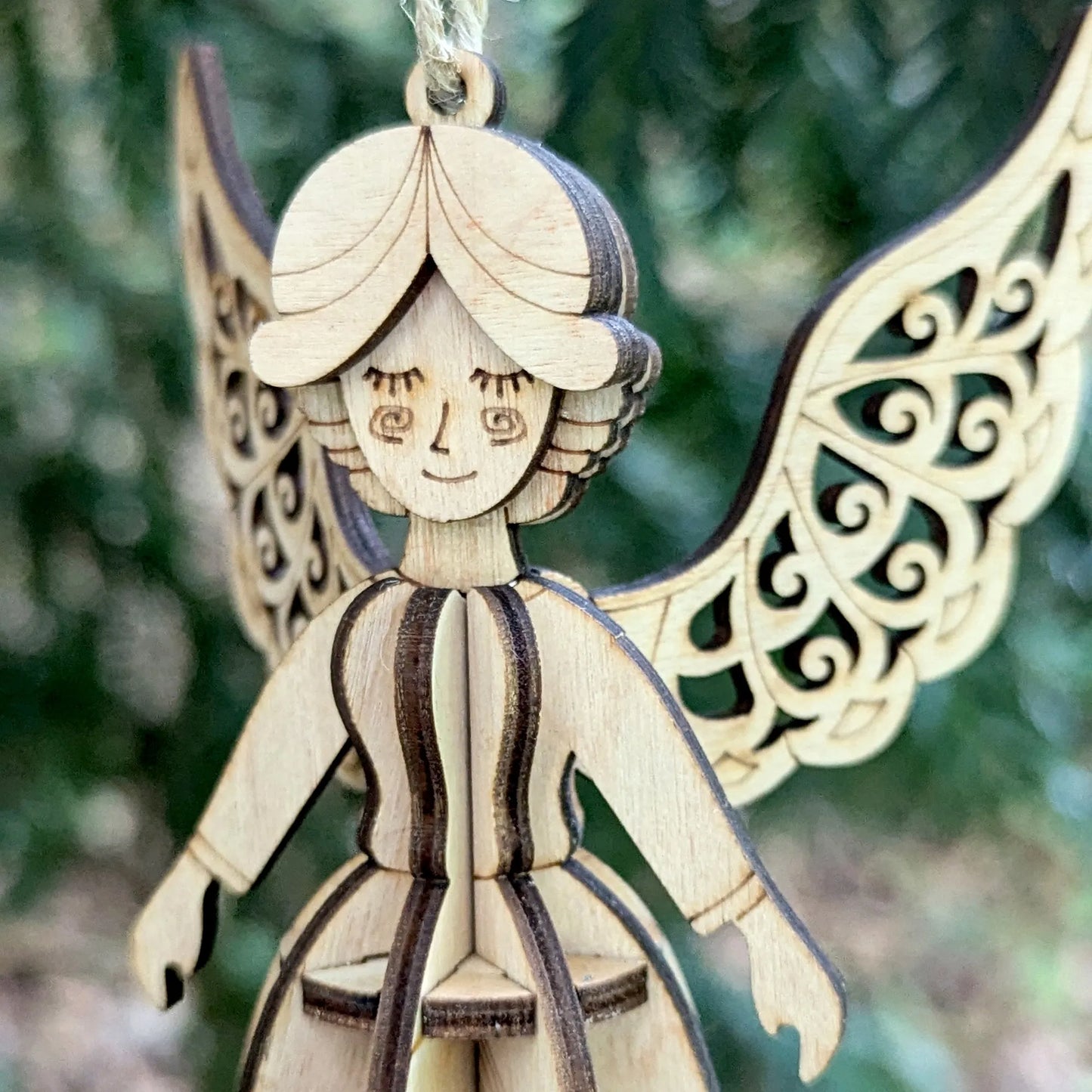 Wooden angel ornament with intricate design against a blurred green background