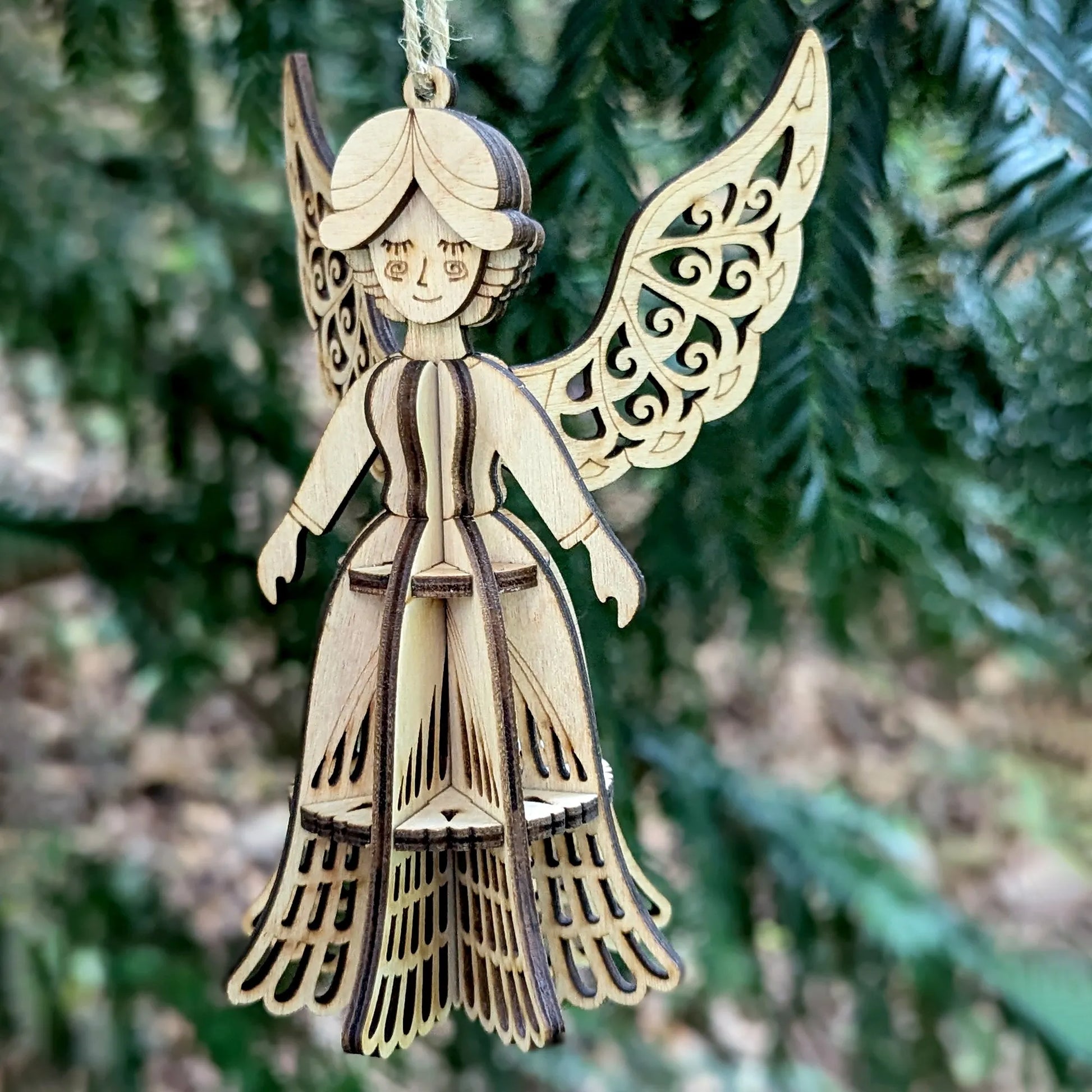 Wooden angel ornament with intricate design hanging on a tree.