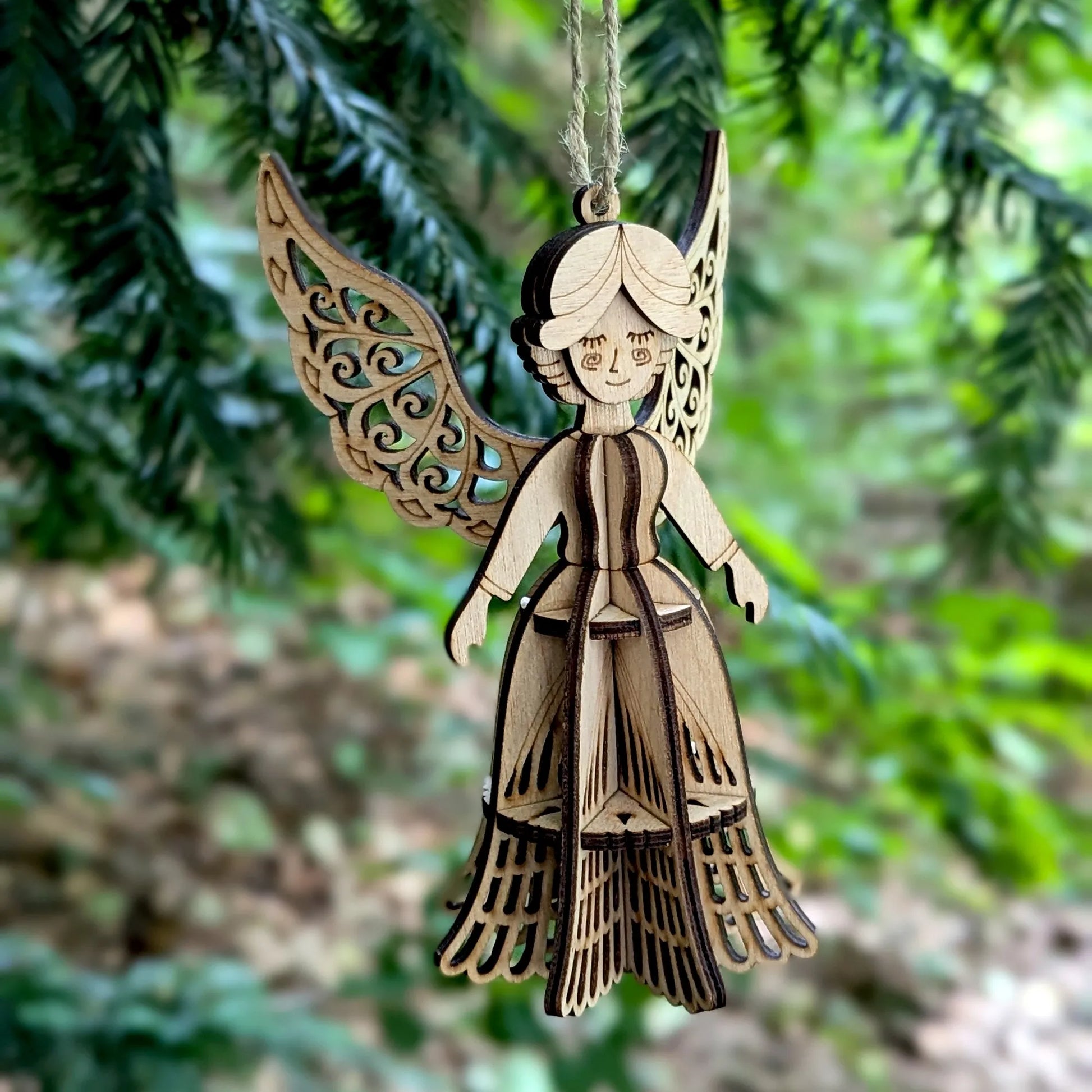 Wooden angel ornament hanging against a green foliage background