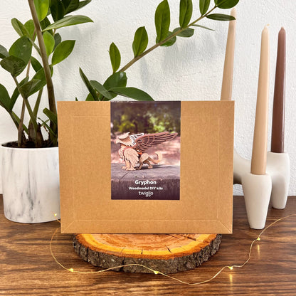 Wooden DIY kit box with a picture of a gryphon on it, placed on a wooden surface with plants and candles in the background.