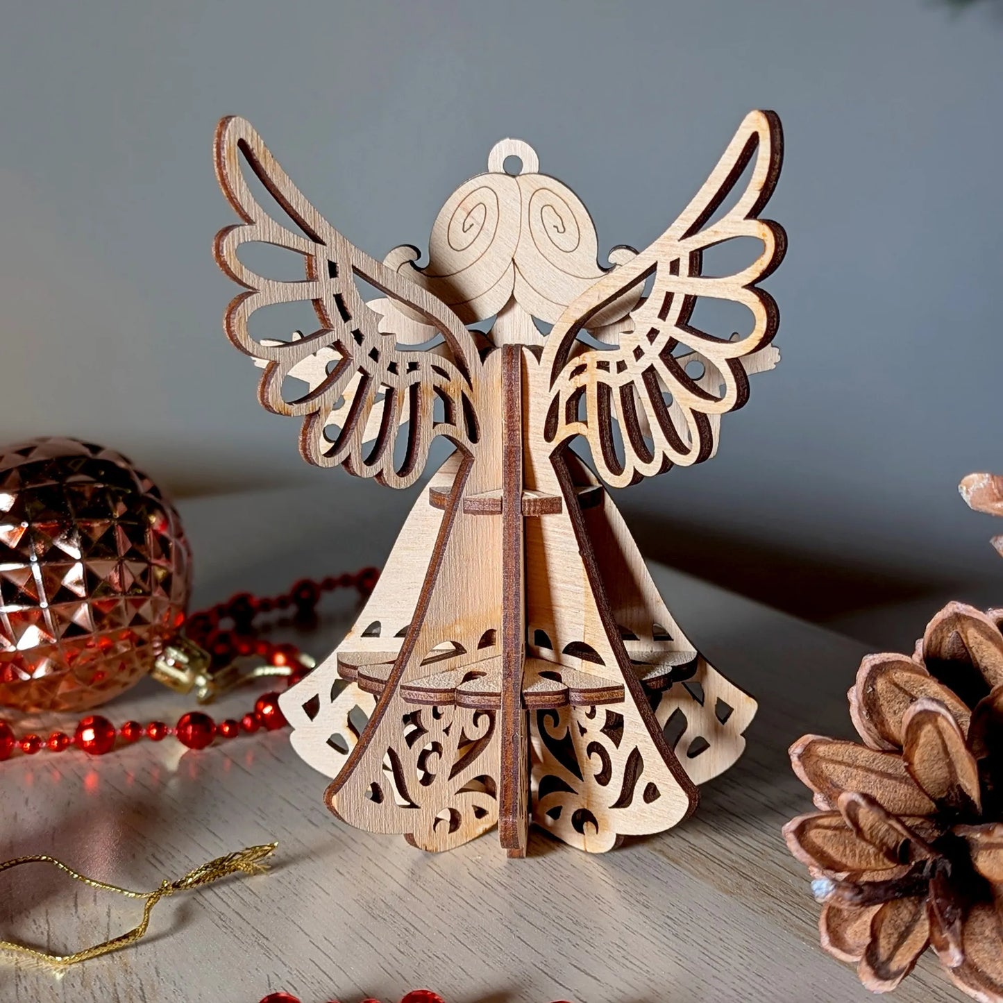 Wooden angel ornament on a wooden surface with decorative items in the background