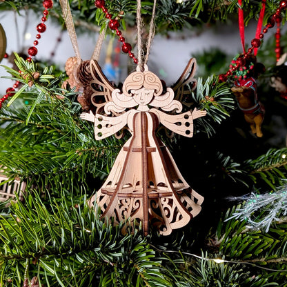 Wooden angel ornament hanging on a Christmas tree with green branches and red decorations.