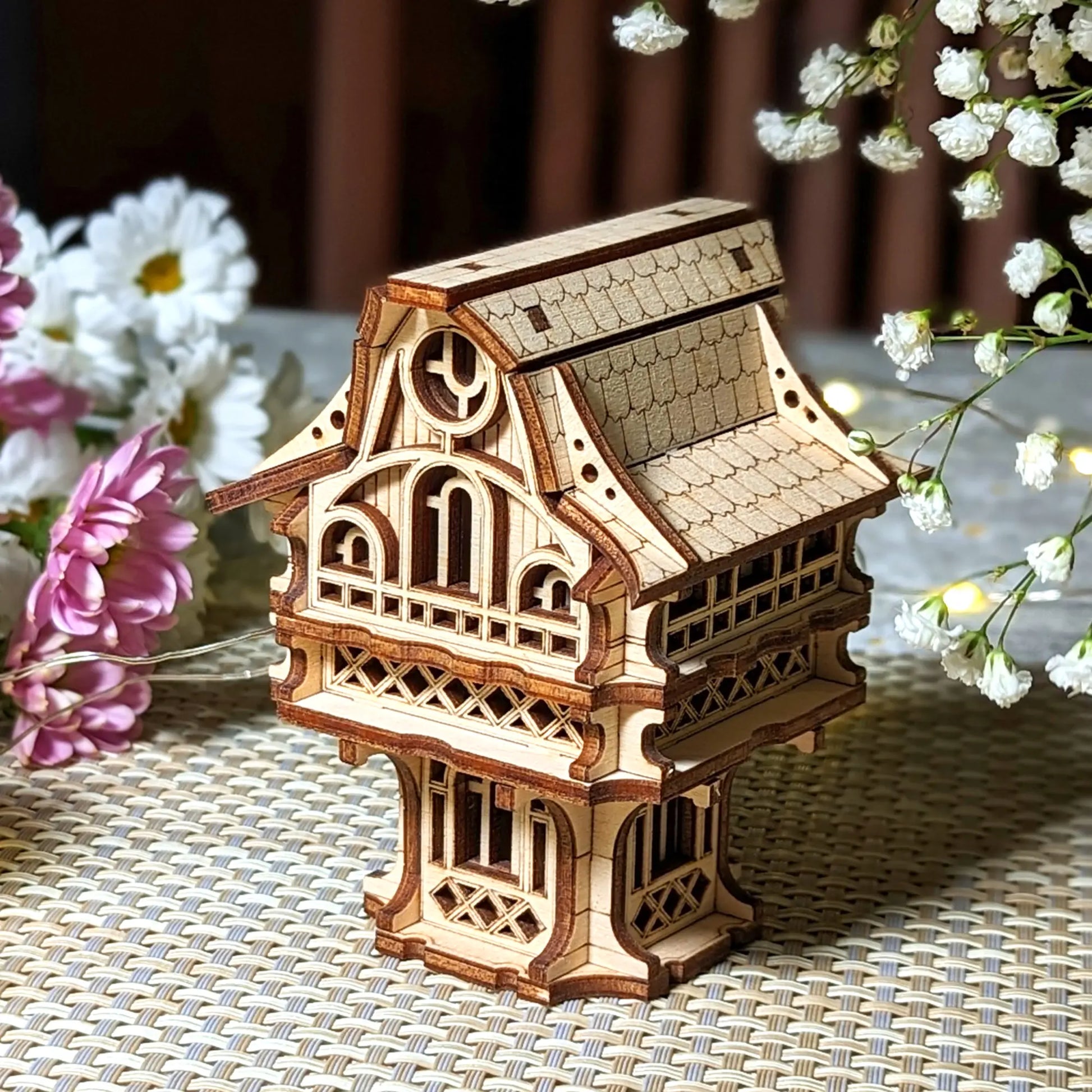 Wooden model of a decorative building with flowers in the background