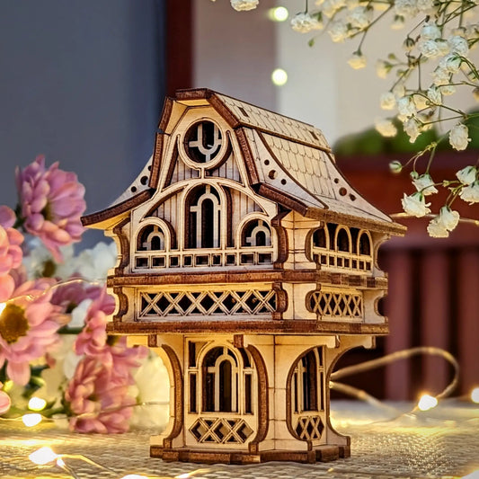 Wooden model of a house with decorative lights and flowers in the background