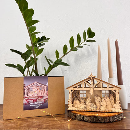 Nativity scene model with a plant and candles on a wooden surface
