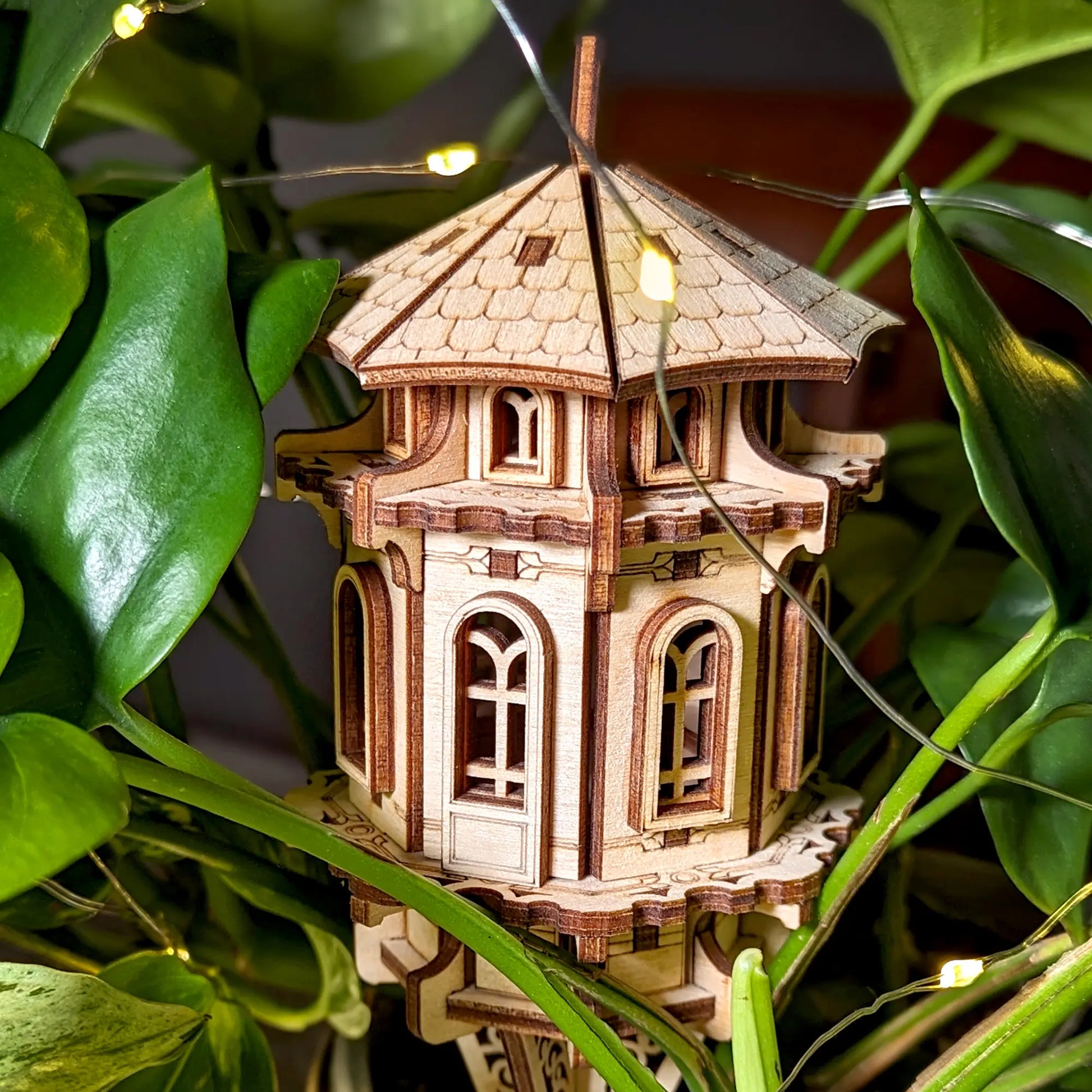 Wooden model of a tower surrounded by green leaves