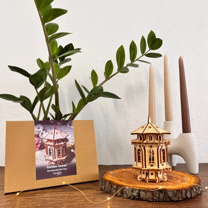Wooden DIY kit packaging with garden tower on a wooden surface with plants and candles in the background.