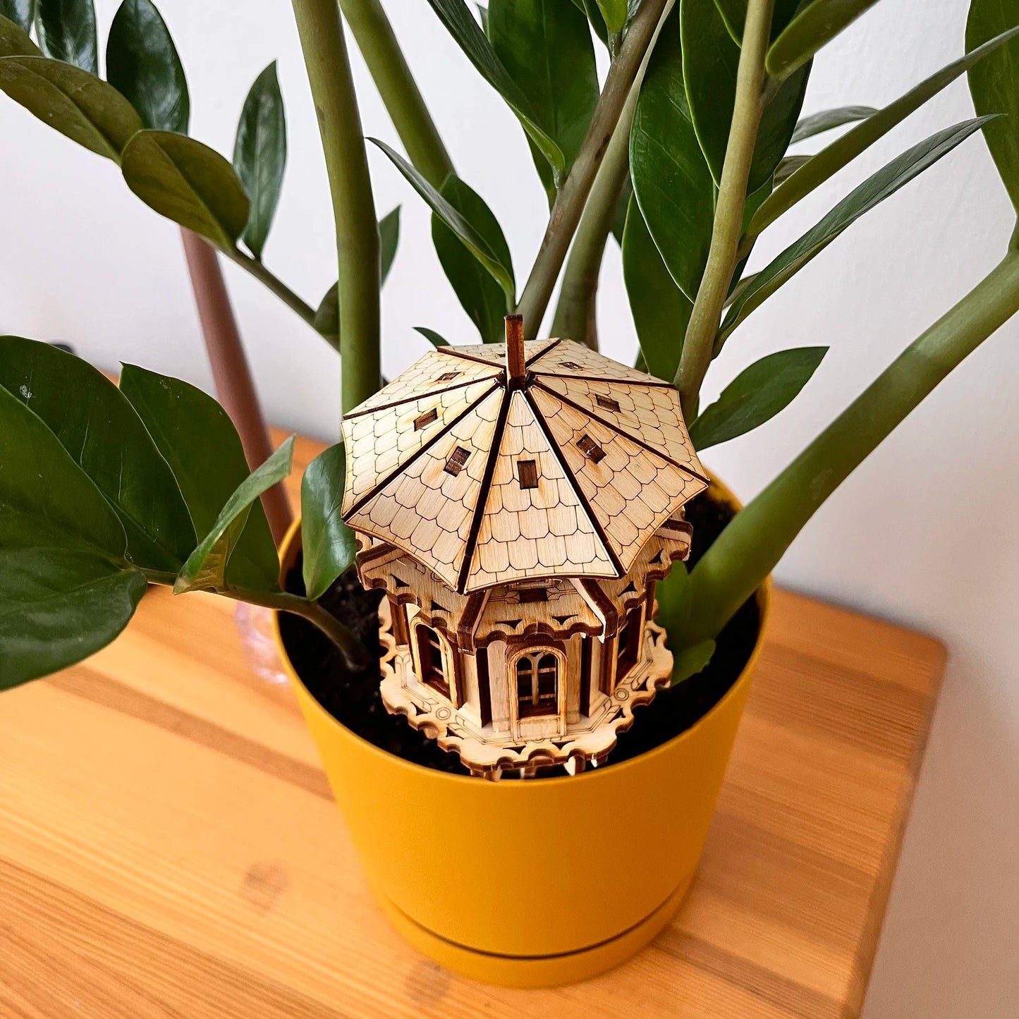 Wooden model of a towerin a potted plant on a wooden surface