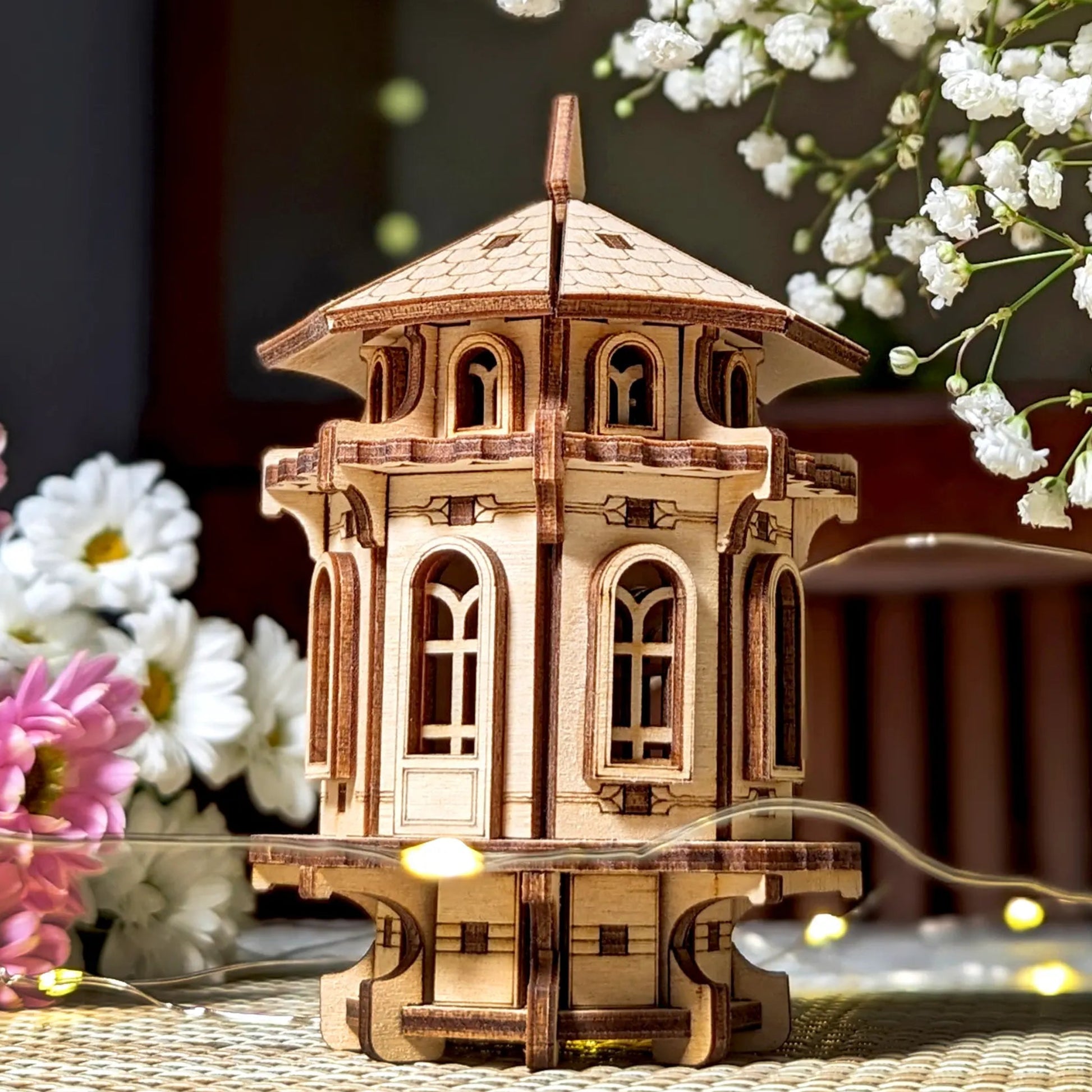 Wooden model of a building with decorative flowers on a textured surface
