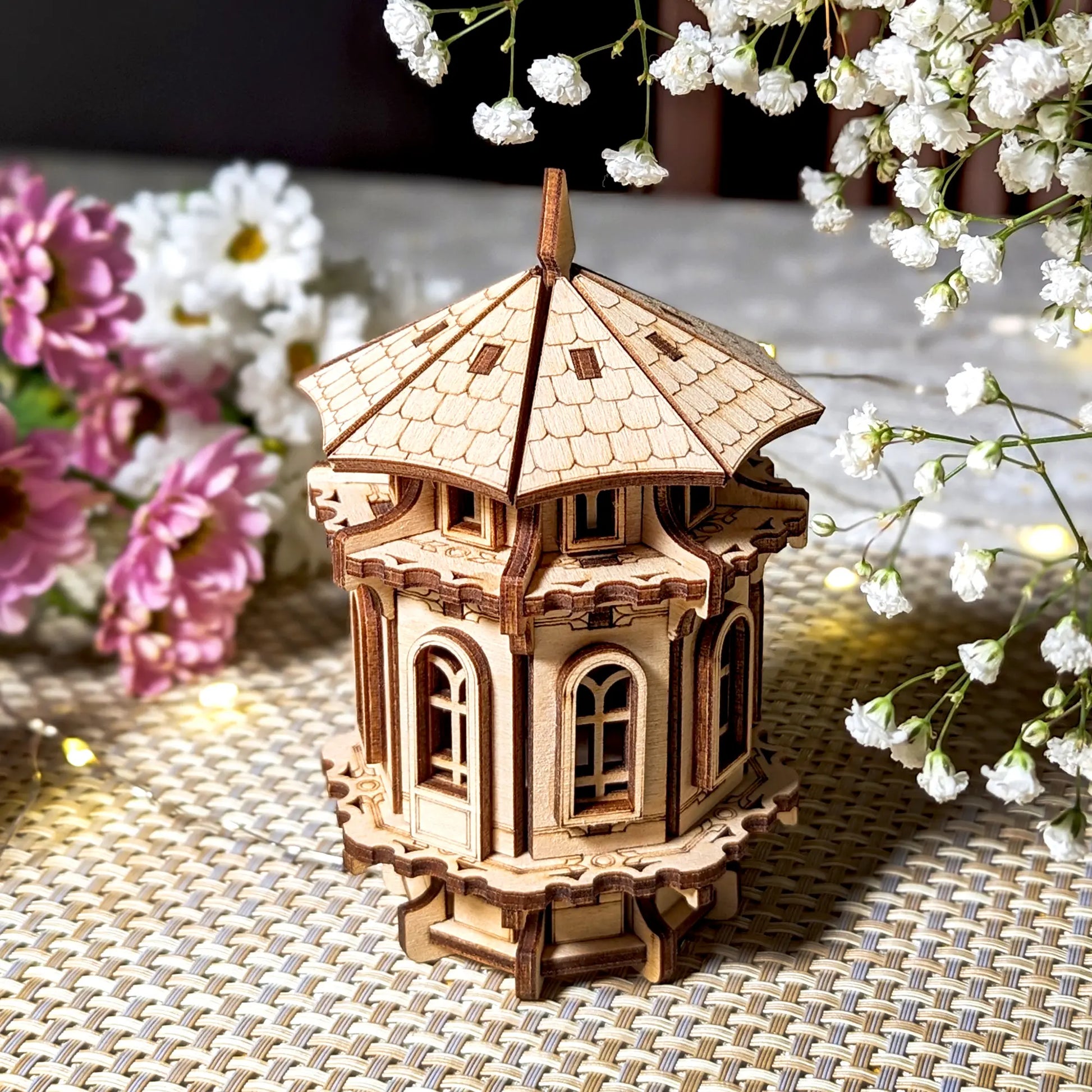 Wooden model of a tower with decorative flowers on a textured surface