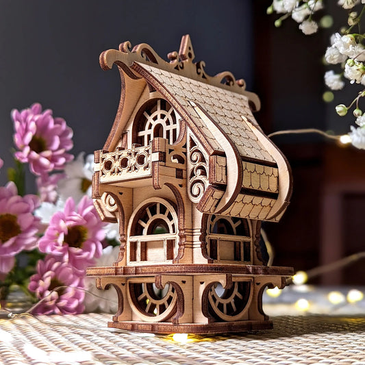 Wooden model of a decorative building with flowers in the background