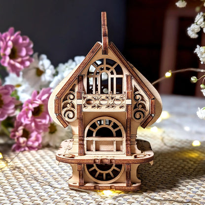 Wooden decorative house model on a textured surface with flowers in the background