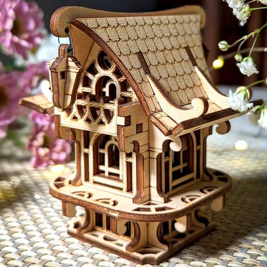 Wooden model of a house on a woven surface with flowers in the background