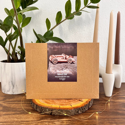 Brown paper bag with a toy car label on a wooden surface with plants and candles in the background