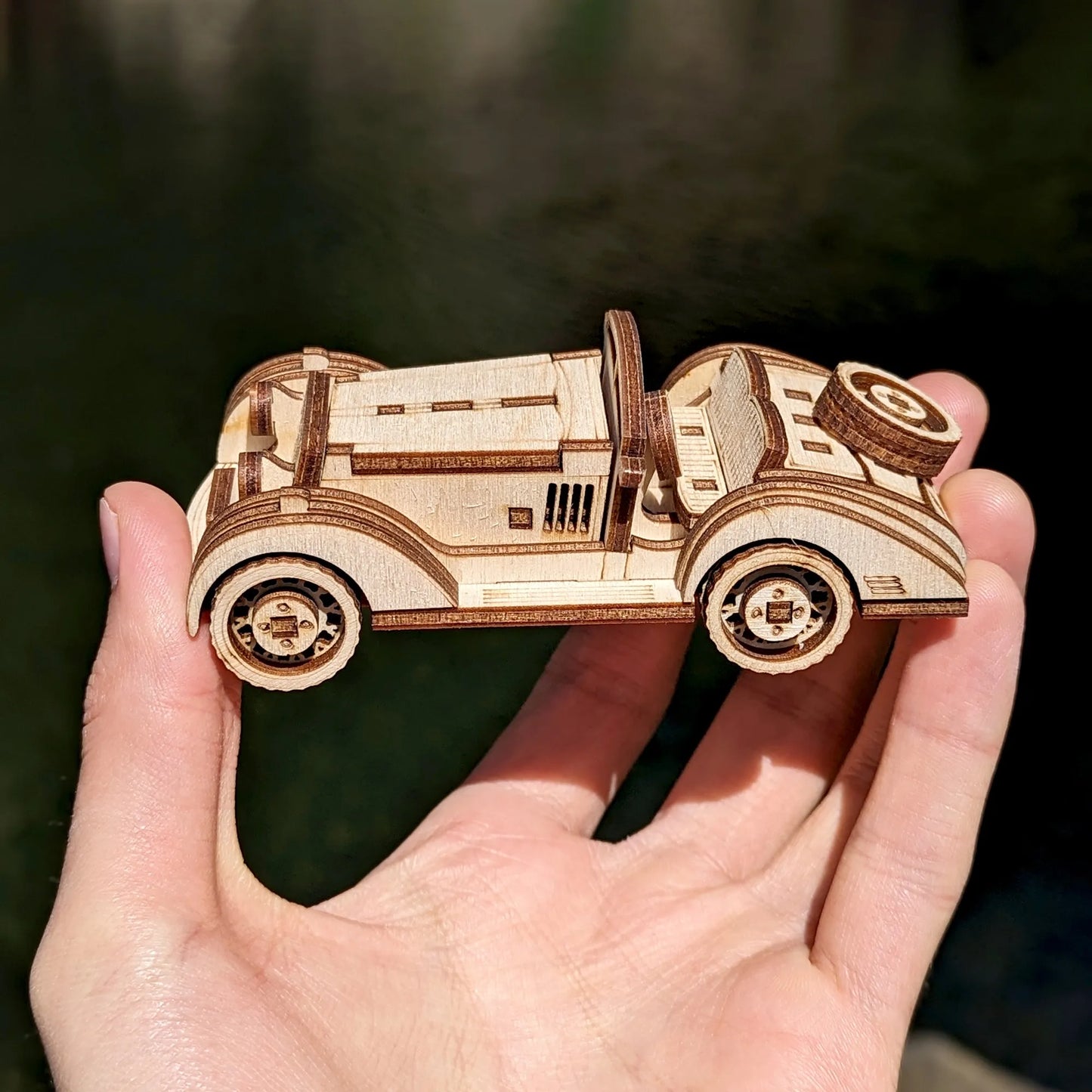 Detailed 3D wooden model of a classic roadster with engraved headlights and retro wheel designs.
