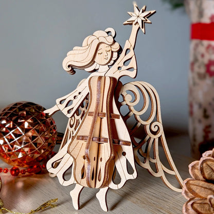 Wooden angel ornament with a star on its head, placed on a surface with a blurred background.