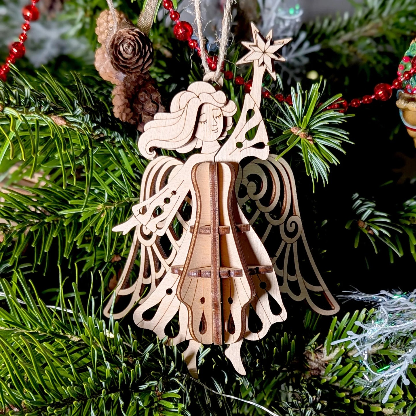 Wooden angel ornament on a Christmas tree with green branches and red decorations.