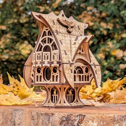 Detailed 3D plywood fairy-tale cottage with ornate roof patterns and gothic-style windows against a blurred fall background.