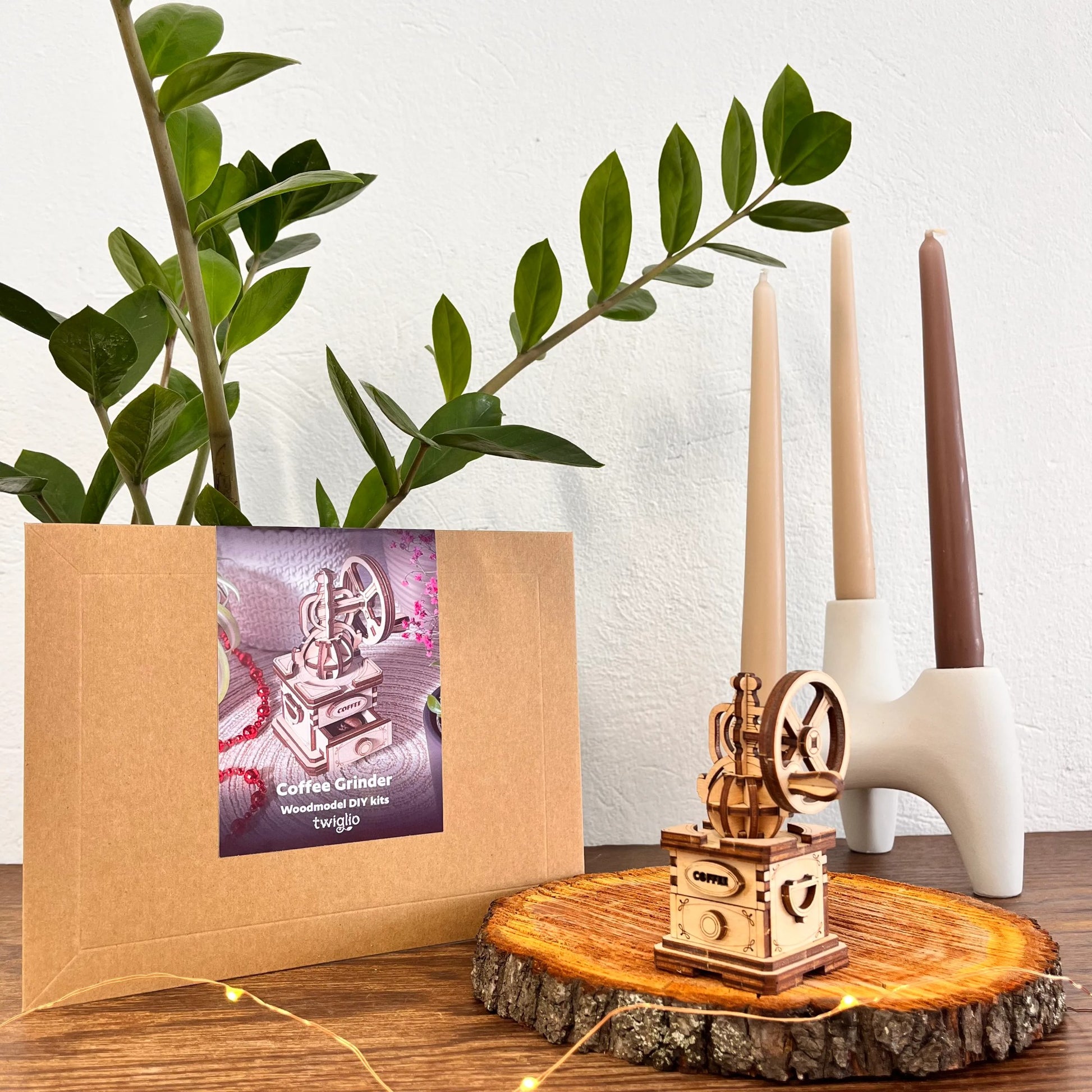 Wooden coffee grinder on a wooden stand with a plant and candles in the background